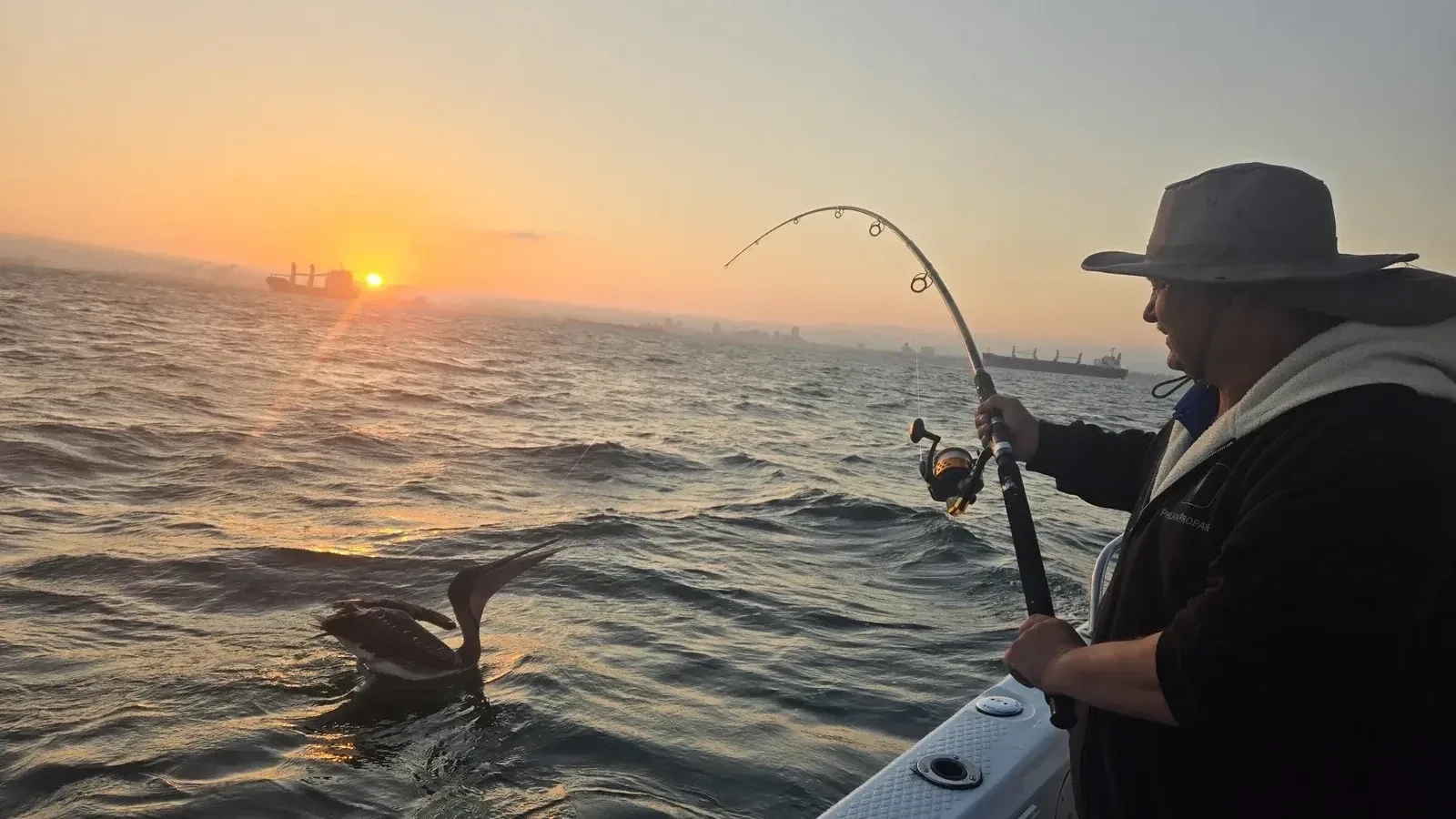 Angler fighting a fish at sunrise