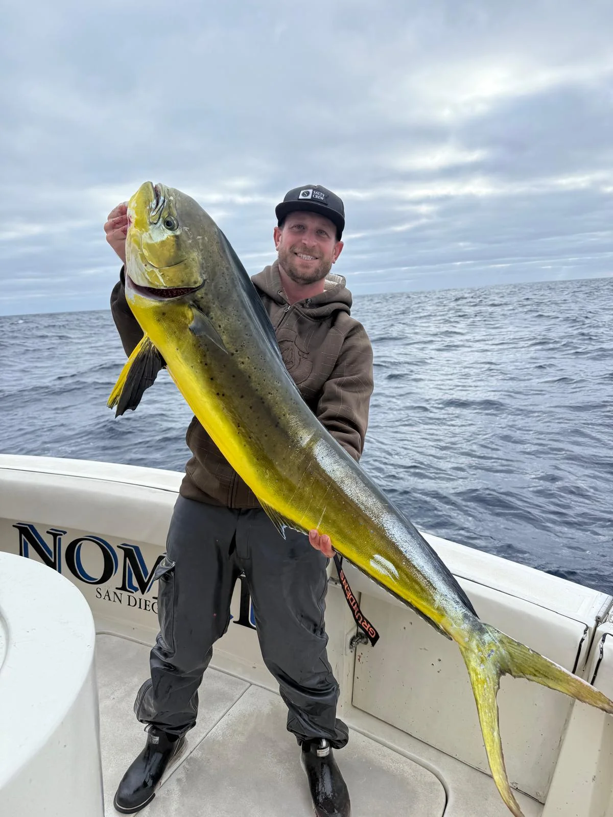 Angler holding a large dorado aboard the NOMAD